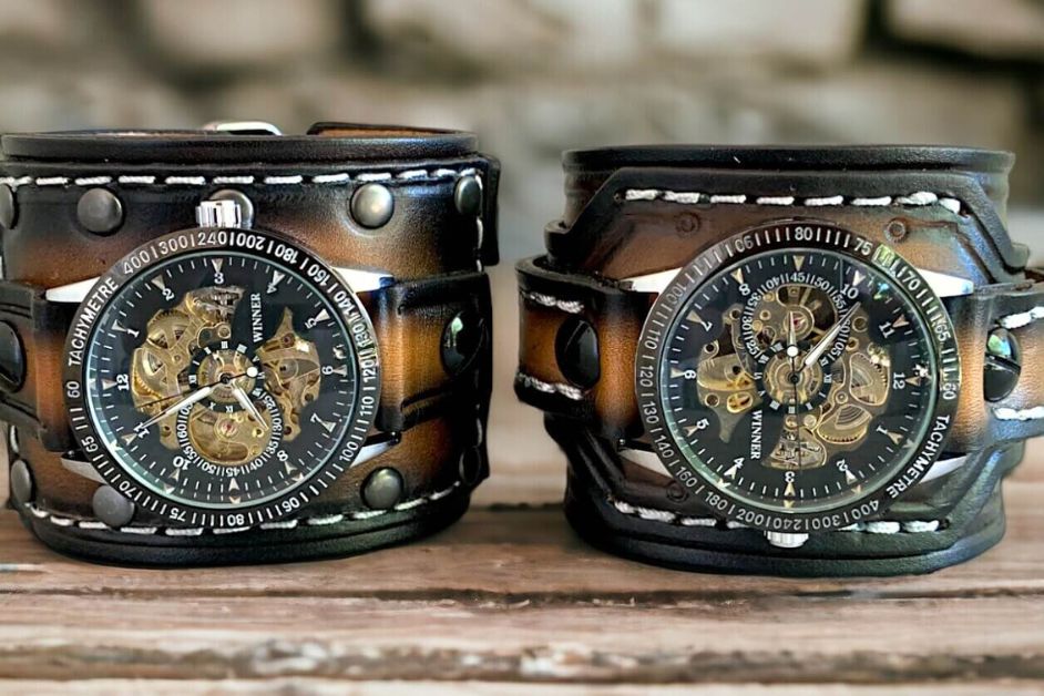 Close-up of a handcrafted leather cuff featuring one of our signature steampunk watches with exposed gears, antique brass hardware, and a vintage mechanical movement.