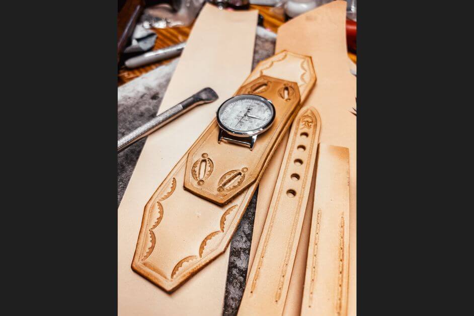 Handmade tan leather Apple Watch band with tooling and craft tools, showing artisan detail and personalization options.